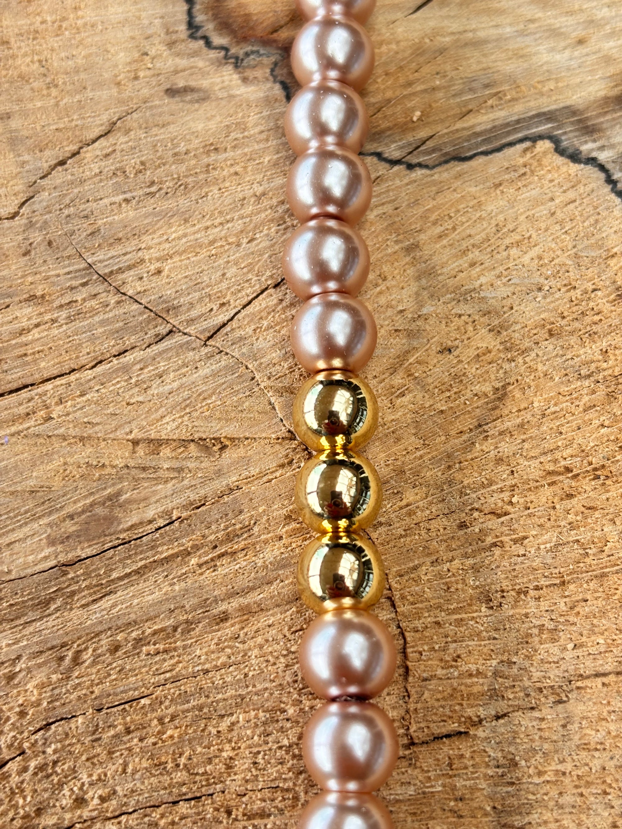 Kort parelsnoer met gouden accenten in taupe brown.